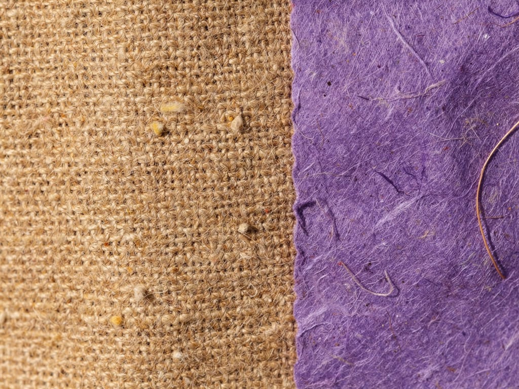 Abstract macro texture of a loose warm sand-coloured linen weave with tiny slubs and gentle shadow, in oat, ochre and so