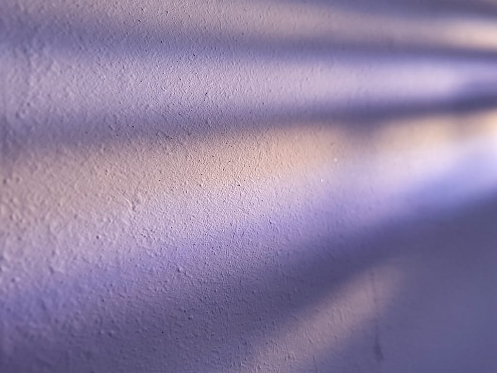 Abstract macro texture of soft lavender light refracting through rippled frosted glass onto a pale plaster wall at dusk,